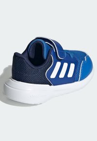 Niebieskie i granatowe trampki dla dzieci z białą podeszwą, trzema białymi paskami po bokach oraz pojedynczym zapięciem na rzep.