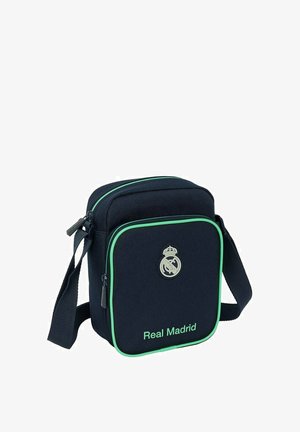 Borsa a tracolla blu navy con accenti verdi, dotata di chiusura con zip, tracolla regolabile e logo del Real Madrid sulla parte anteriore. Tessuto testurizzato.