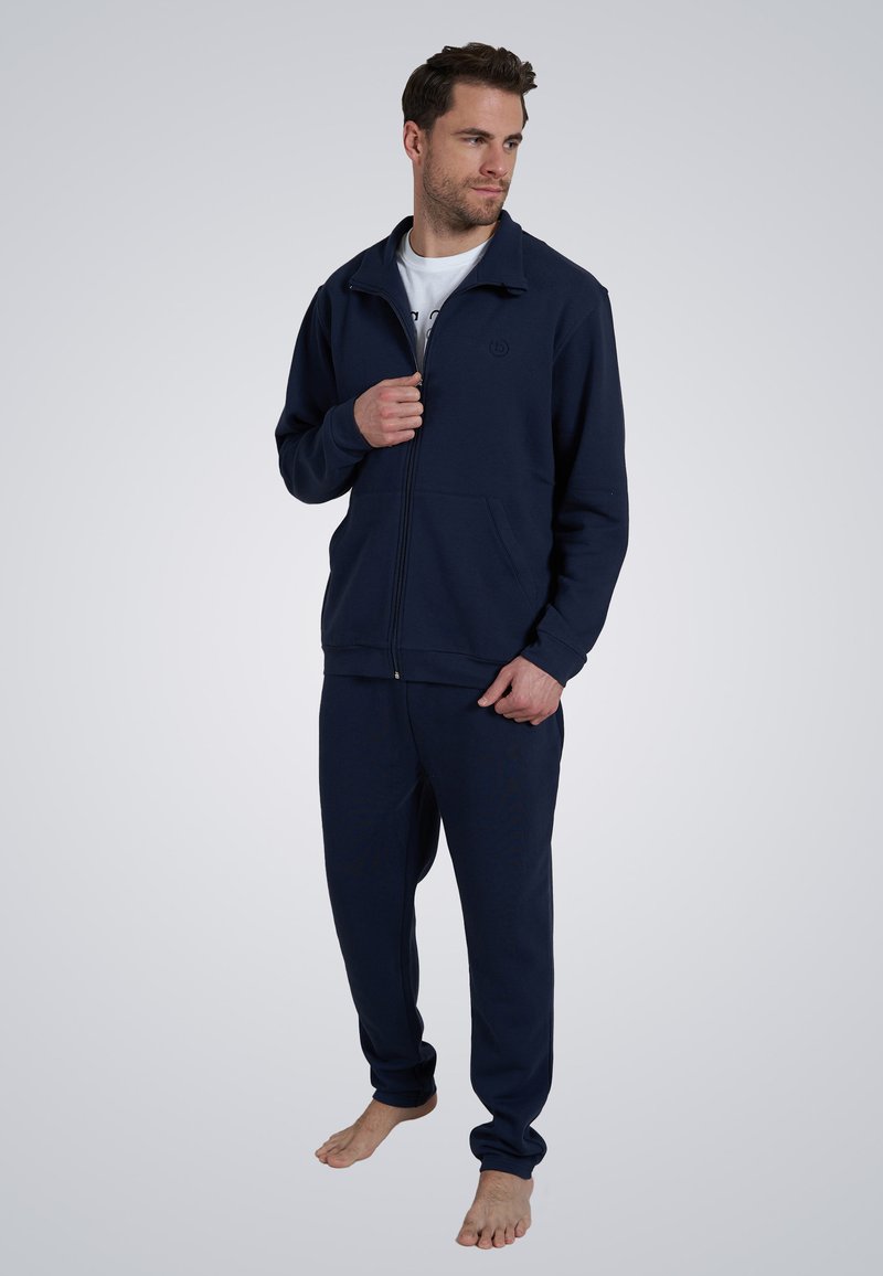 Marinefarbener Reißverschluss-Pullover mit Fronttaschen und passender Jogginghose, aus weichem Stoff gefertigt, mit einem Logo auf der Brust, schlichtes Design.