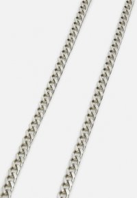 Hopeinen metalliketju, jossa on suuret, toisiinsa lukkiutuvat lenkit, kiillotettu pinta ja sileä tekstuuri.