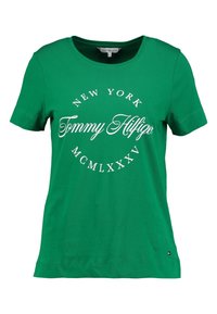 Camiseta de algodón verde con mangas cortas, que presenta un estampado circular blanco que incluye el texto "Nueva York" y "Tommy Hilfiger".