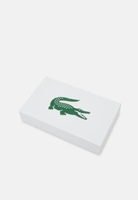 White rectangular box featuring a green crocodile logo, with a smooth surface and clean edges, designed for product packaging.