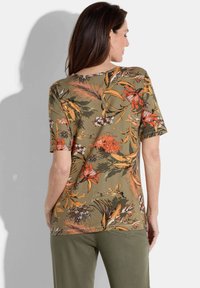 Korte mouwen shirt met een bloemmotief in oranje en wit op een olijfgroene achtergrond, met een ronde hals en een relaxte pasvorm.