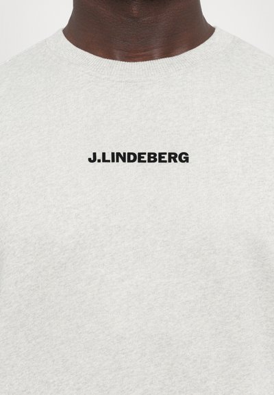 Grå bomullssweatshirt med rund hals. Har en svart trykt logo "J.LINDEBERG" på framsiden. Struktureret stoff.