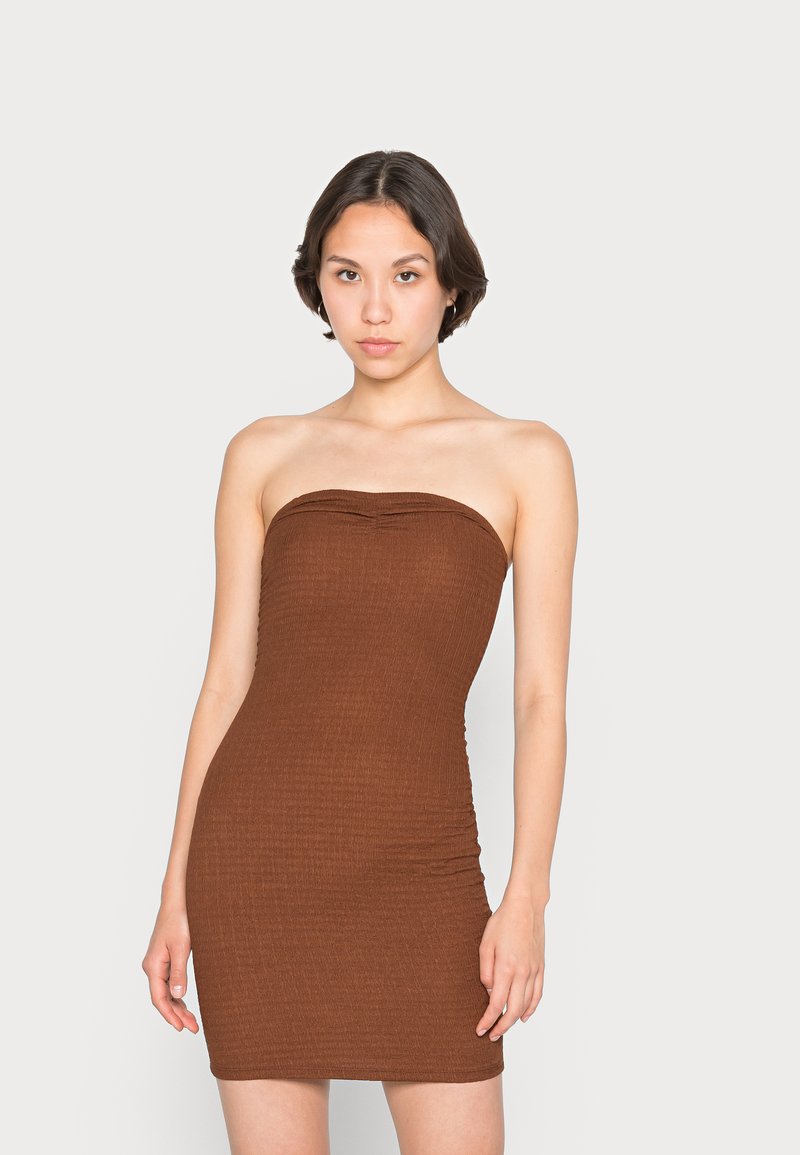 Vestido bodycon castanho, sem alças, feito de um tecido texturizado, com uma silhueta ajustada e pregas subtis nas laterais.