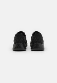 Zapatillas negras con parte superior de tejido texturizado y suelas de goma lisas, que cuentan con un diseño sin costuras y un talón redondeado para mayor comodidad.