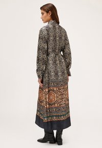 Rochie lungă, cu model, ce prezintă o combinație de nuanțe de albastru închis, auriu și tonuri pământii; material ușor; mâneci lungi; talie strânsă.