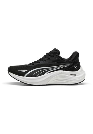 Chaussure de sport noire avec tige en mesh, semelle intermédiaire en caoutchouc blanc et semelle extérieure texturée. Présente un design incurvé et des accents blancs subtils.