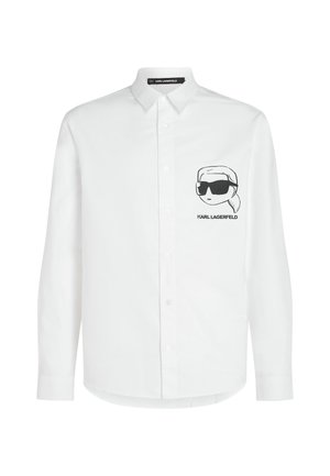 Valge puuvillasegust nööbitav särk, millel on vasakul rinnal must tikand, millel on prillidega karakter.