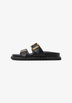 Sandalias deslizantes de cuero negro con dos correas anchas, hebillas doradas y una suela negra resistente que presenta una fila de pequeños tachuelas.