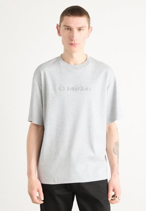 Gray cotton t-shirt with short sleeves and a crew neckline. Features embossed "Calvin Klein" logo on the chest. Straight-cut design.