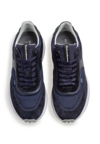 Baskets de sport bleu marine avec un mélange de textures en mesh et en daim, présentant un bout arrondi, des lacets et une semelle translucide.