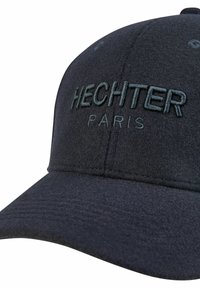 Donkerblauwe pet van zacht fabric, met geborduurde tekst "HECHTER" en "PARIS" in donkere tinten, voorzien van een gestructureerde klep en subtiele textuur.