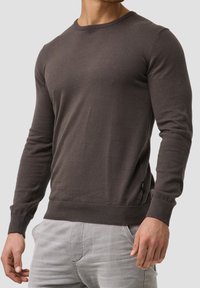 Dark brown long-sleeve sweater in a soft knit fabric. Features a round neckline and ribbed cuffs and hem for a fitted look.
