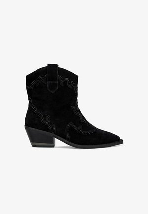 Black suede cowboy boots feature a pointed toe, low block heel, and decorative stitching with stud accents along the sides and top edge.