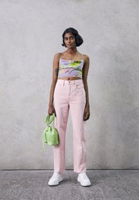 Top floral em lavanda cortado, jeans rosa claro de perna reta, ténis brancos e uma mala estilo baldei mint com cordão.