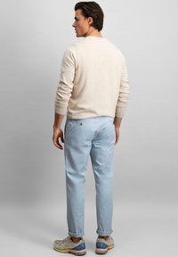 Pulover bej deschis cu mâneci lungi, asortați cu pantaloni bleumarin deschis. Completat cu tivuri rulate și teniși gri cu accente albastre.