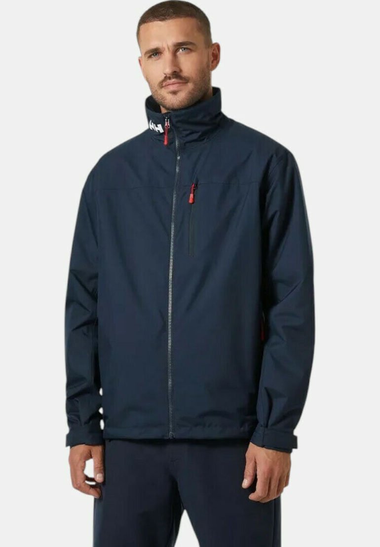 Chaqueta impermeable azul marino con un alto cuello, cremallera frontal, bolsillo en el pecho con cremallera y acentos rojos en las cremalleras y puños.