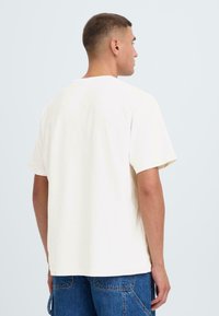 Kortærmet beige t-shirt med en afslappet pasform, lavet af blødt bomuld, med en rund halsudskæring og glat tekstur. Simpelt design uden pynt.