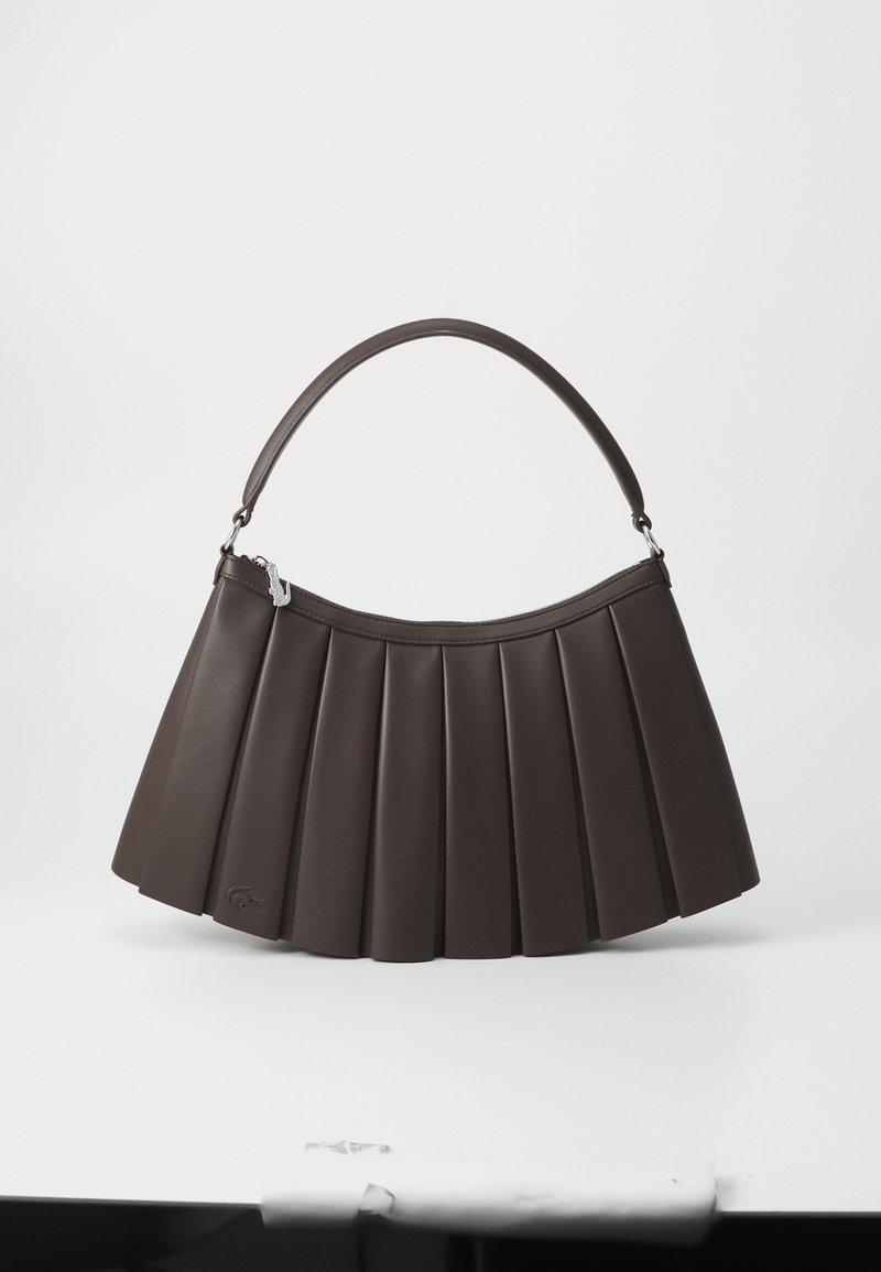 Sac à main en cuir plissé brun foncé avec une petite anse incurvée et un petit logo de crocodile dans le coin inférieur gauche.