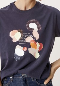Camiseta de algodón azul marino con un colorido estampado abstracto que presenta formas pastel superpuestas y texto en un diseño central. Manga corta.