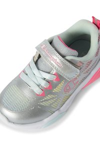 Scarpa sportiva argento con design in rete, dettagli rosa e cinturino regolabile. Presenta una superficie testurizzata e un interno imbottito per il comfort.
