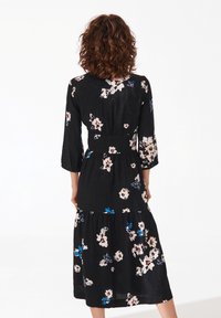 Abito floreale nero con maniche a tre quarti, caratterizzato da una gonna a strati e motivi di fiori rosa e blu. Tessuto morbido e vita aderente.