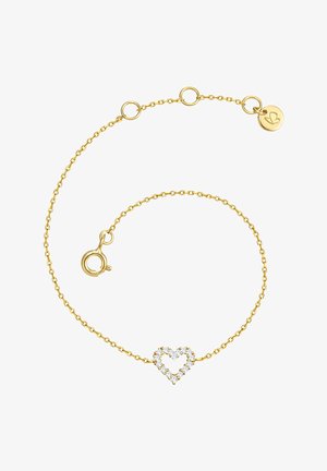 Bracelet en chaîne dorée avec un charme en forme de cœur ouvert fait de petites pierres blanches et une petite étiquette ronde en or avec un motif gravé.