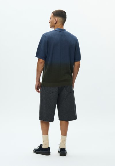 Πλεχτό πουκάμισο με κοντά μανίκια και διαβάθμιση από σκούρο μπλε σε πράσινο, σε συνδυασμό με σκούρο τζιν σορτς. Διαθέτει γιακά και άνετη εφαρμογή.