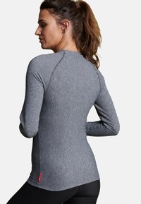 Maglietta sportiva a maniche lunghe in tessuto grigio melange. Presenta un design aderente con maniche raglan e una cucitura orizzontale vicino all'orlo.