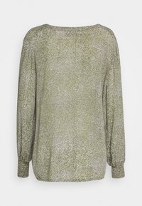 Blouse verte à manches longues en tissu léger et doux. Arbore un motif abstrait blanc délicat et un col rond avec des poignets élastiques.