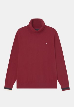 Pull en maille rouge avec col roulé côtelé, manches longues et rayures contrastantes aux poignets. Petit logo en accent sur la poitrine.