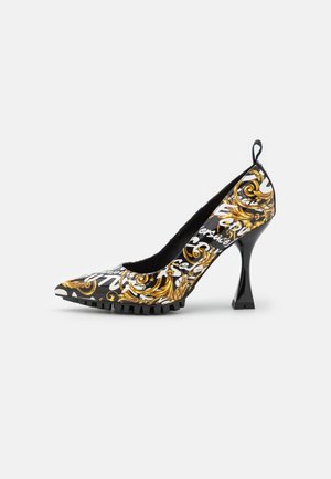 Zwarte hoge hak schoen met gouden barokpatronen, witte scripttekst overlay, spitse neus, gestructureerde zool en gebogen stilettohak.