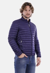 Giacca imbottita viola con zip frontale, colletto alto e tasche laterali. Presenta un design trapuntato e una texture liscia e lucida.