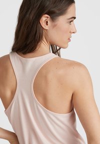 Ljusrosa sporttopp med racerback-design, mjuk textur och en lös passform. Synliga sömmar och slät tyg som faller över axlarna.