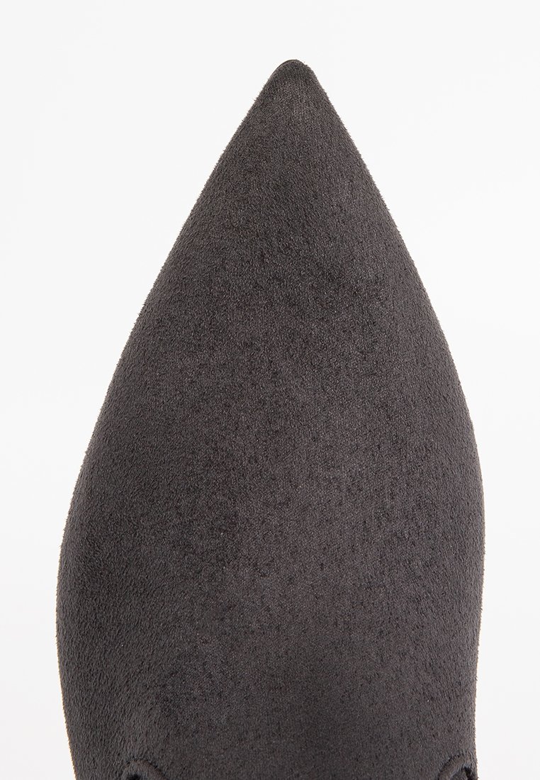 Schwarzer Wildleder-Schuh mit spitzem Zehenbereich, der eine glatte Textur aufweist. Das Design ist schlank mit einer scharfen Silhouette und betont Eleganz und Einfachheit.