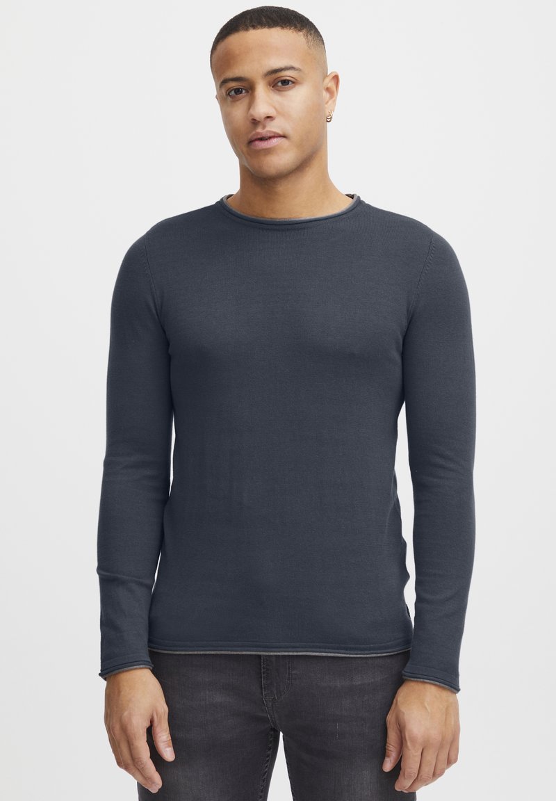 T-shirt aderente a maniche lunghe di colore grigio scuro, realizzata in materiale morbido, con scollatura rotonda e dettagli di cucitura discreti lungo l'orlo.