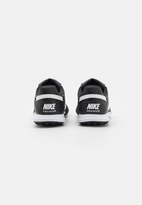 Black Nike Premier cleats with white accents, featuring a textured upper, cushioned heel, and traction studs on the sole.