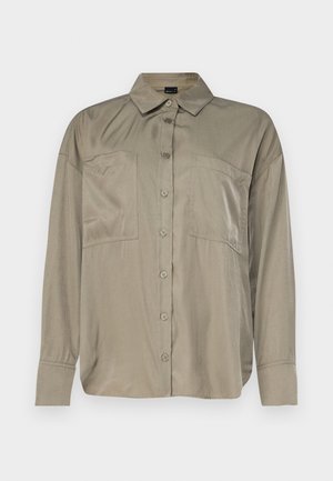 Camisa de color verde oliva, de manga larga, en una tela suave y ligera. Presenta un cierre de botones en el frente, cuello puntiagudo y dos bolsillos en el pecho.