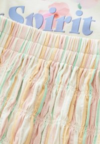Tissu rayé multicolore aux teintes pastel de rose, jaune et vert. La texture est froncée avec un détail de smock en élastique.