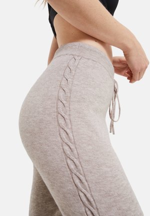 Pantalons de survêtement gris clair en tissu doux, avec un détail en tricot câblé texturé sur le côté et une taille avec cordon de serrage.