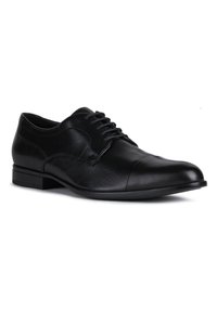 Chaussure de ville noire en cuir avec un bout arrondi, un laçage et des détails de couture subtils sur les côtés. Texture lisse et petit talon.