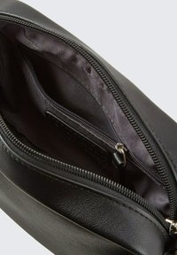 Schwarze Leder-Umhängetasche mit Reißverschluss, die über eine glatte Außenseite und ein weiches Innenfutter mit zusätzlichem Reißverschlussfach verfügt.
