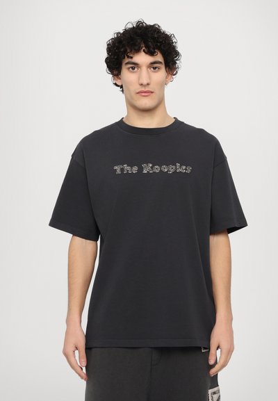 Fekete pamut póló rövid ujjakkal és kerek nyakkal, csillogó "The Kooks" felirattal a mellkason. Lazán illeszkedő fazon.