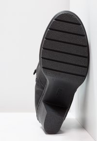 Czarne skórzane botki na kostkę z gumową podeszwą, teksturowanym bieżnikiem i niskim obcasem słupkowym. Zamek błyskawiczny z boku do zapięcia.