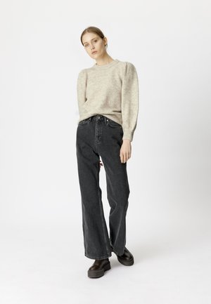Beige textuur pullover trui met puffed mouwen, gecombineerd met hoge taille zwarte wijde spijkerbroek en chunky zwarte platform enkellaarsjes.