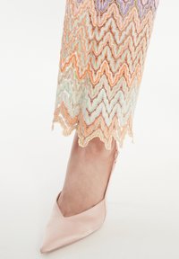 Paarse satijnen puntenhak met een lage achterkant, gecombineerd met een meerkleurige zigzagpatroon kanten zoom met pastelachtige oranje en aqua tinten.