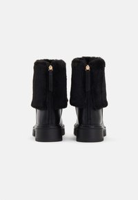 Bocanci negri până la gleznă, cu un manșon din blană artificială, corp din piele netedă, fermoar pe spate cu accesorii aurii și talpă din cauciuc texturat.
