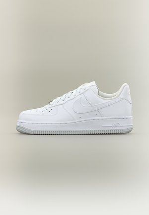 Witte lage Nike Air Force 1 sneaker met veters, geperforeerde neus en gestructureerde rubberen zool op neutrale achtergrond.