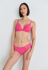Pink lace bra with molded cups and adjustable straps, paired with matching pink lace brief featuring a smooth waistband and floral detail.